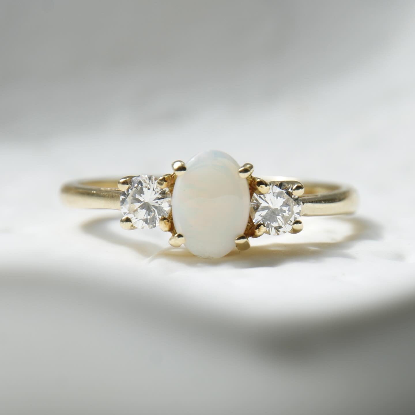 Pre-Owned Opal and Diamond three stone ring set in an exquisite 18ct yellow gold band . Her impressive 0.75ct opal offers beautiful flashes of colour and is partnered by round brilliant cut diamonds.