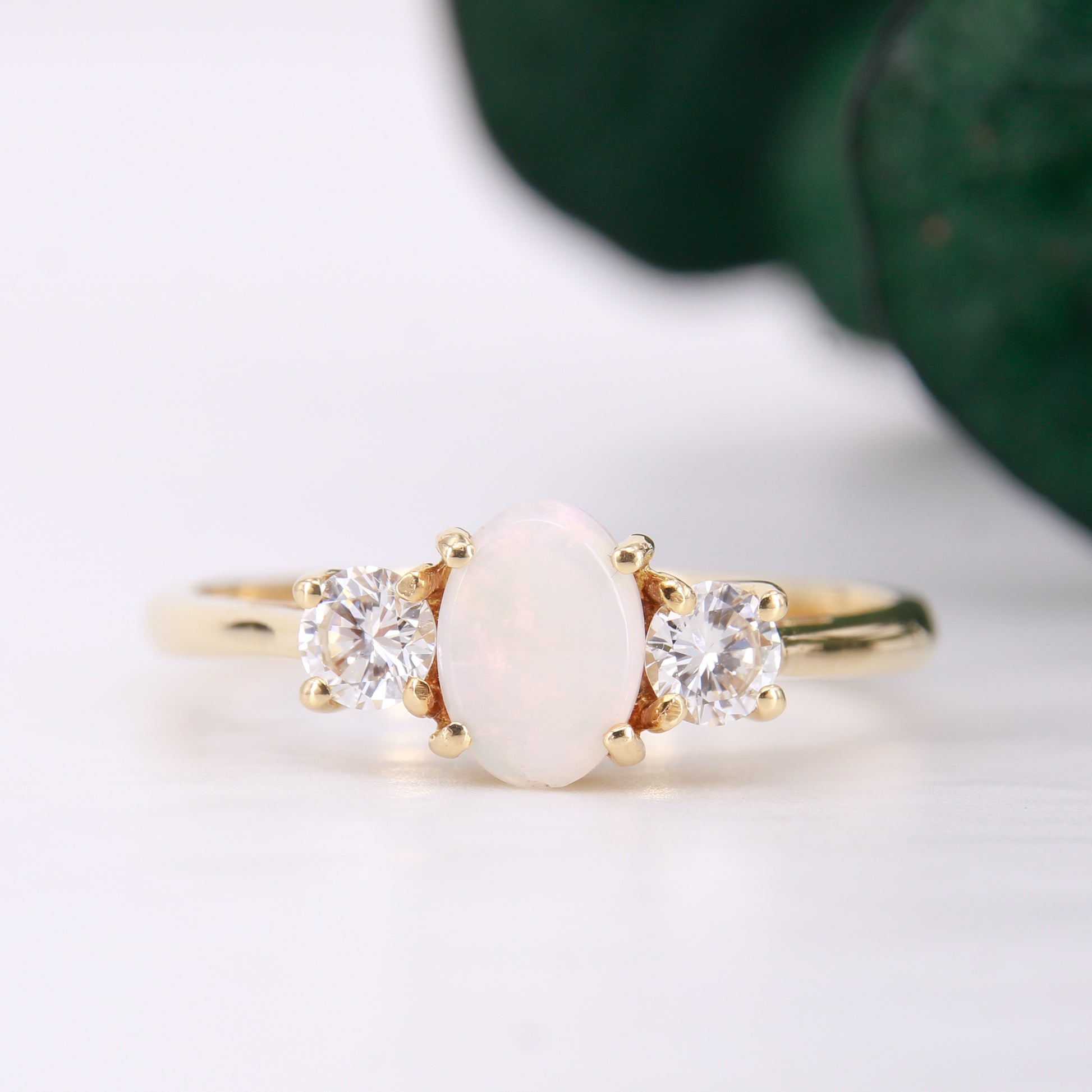 Pre-Owned Opal and Diamond three stone ring set in an exquisite 18ct yellow gold band . Her impressive 0.75ct opal offers beautiful flashes of colour and is partnered by round brilliant cut diamonds.