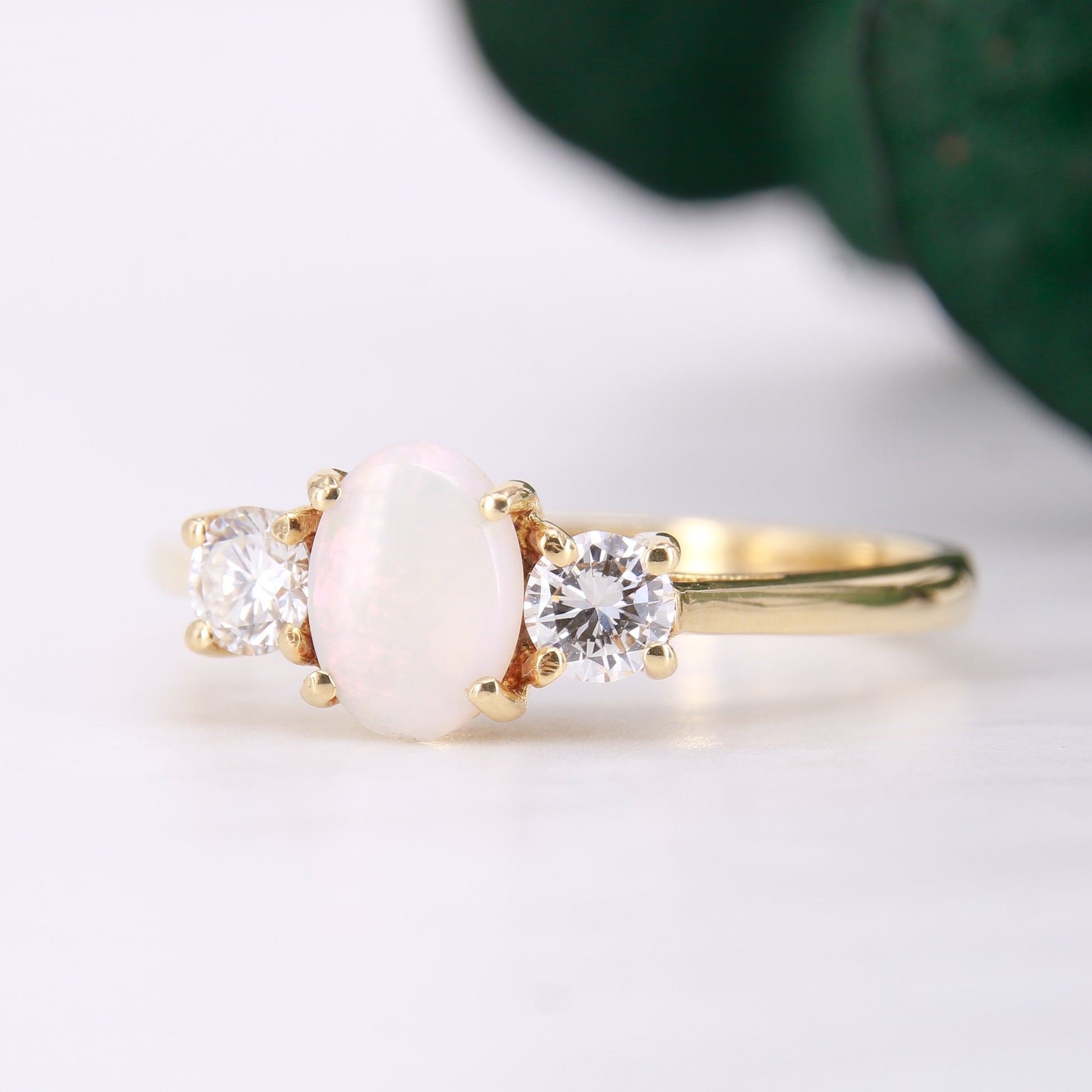 Pre-Owned Opal and Diamond three stone ring set in an exquisite 18ct yellow gold band . Her impressive 0.75ct opal offers beautiful flashes of colour and is partnered by round brilliant cut diamonds.