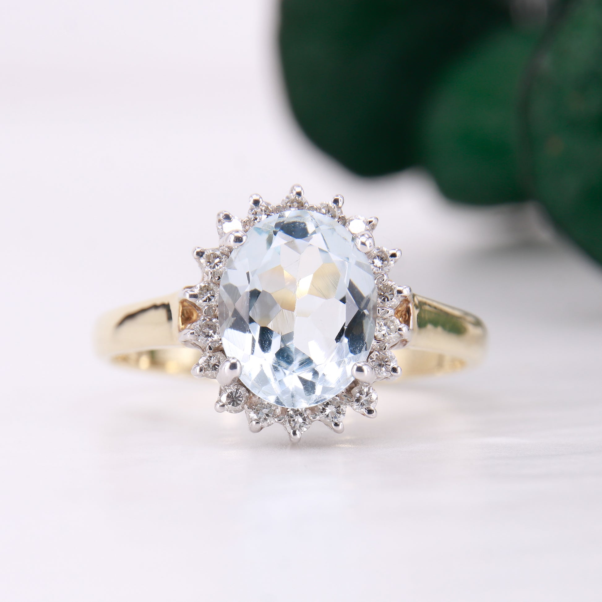 Preowned Aquamarine and Diamond Preowned Ring. Oval cut Aquamarine with a halo of diamonds set in 9ct yellow gold. 