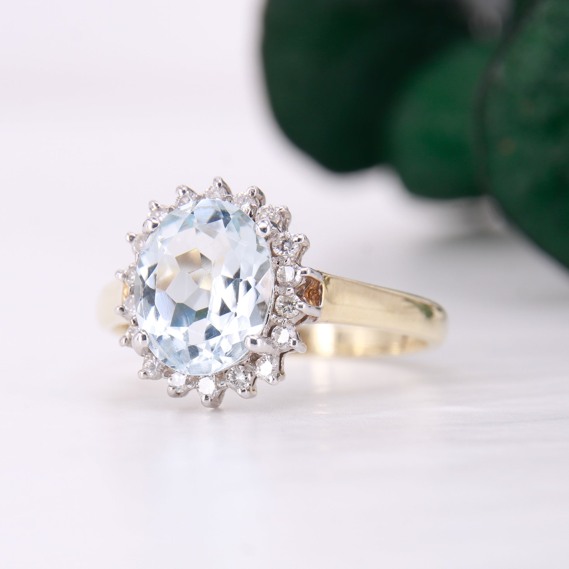 Preowned Aquamarine and Diamond Preowned Ring. Oval cut Aquamarine with a halo of diamonds set in 9ct yellow gold. 